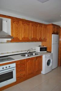 cocina con armarios de madera, fregadero y lavavajillas en APARTAMENTO TURISTICO EL ACEBO, en Jarandilla de la Vera