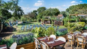 un patio con mesas y sillas en un jardín en The Great House, Sonning, Berkshire en Reading