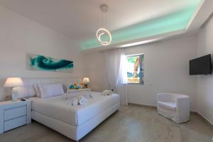 1 dormitorio blanco con 1 cama blanca y TV en Villa Amethyst, en Porto Heli