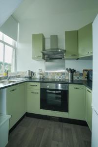a kitchen with white cabinets and a black oven at Marys Garden View North in Jedburgh
