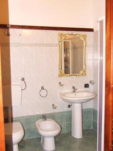 uma casa de banho com um lavatório, um WC e um espelho. em L'Uliveto em Reitano
