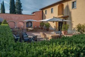 un patio con mesas, sillas y sombrillas en Il Borghetto Tuscan Holidays, en San Gimignano