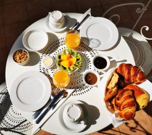 a white table with a breakfast of croissants and orange juice at Auberge de la Tour in Saint-Jean-de-Valériscle