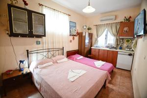 a bedroom with two beds with pink sheets and a kitchen at Ikaria Studios in Manganítis