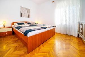 a bed in a bedroom with a wooden floor at Apartmant Ivan in Malinska