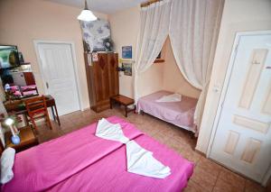 a bedroom with a pink bed and a desk at Ikaria Studios in Manganítis