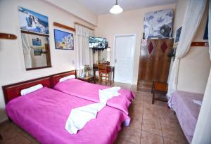 a bedroom with two beds with pink sheets and a table at Ikaria Studios in Manganítis