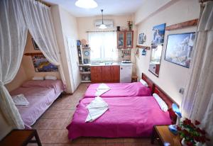 two beds in a small room with pink sheets at Ikaria Studios in Manganítis
