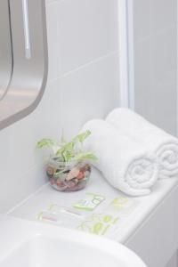 a white towel sitting on a shelf next to a plant at Zest Jemursari by Swiss-Belhotel International in Surabaya