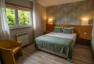 a bedroom with a bed and a chair and a window at Paraíso Douro AL in Lamego