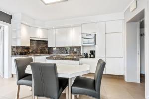 uma cozinha com armários brancos e uma mesa e cadeiras brancas em Holiday house Villa Victoria em Diksmuide