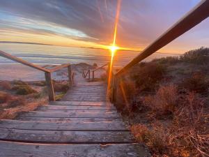 a wooden path leading to the beach at sunset at Langebaan Beach Towers in Langebaan