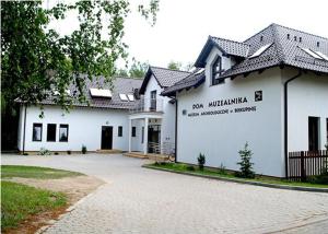 een wit gebouw met een bord aan de zijkant bij Muzeum Archeologiczne w Biskupinie - Dom Muzealnika in Biskupin