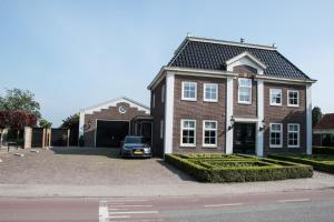 a house with a car parked in front of it at De tien Wilgen in Oosterblokker