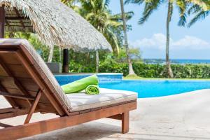 a lounge chair next to a swimming pool at Unique Villa with Ocean and River Views - Staff & Golf Carts in La Romana