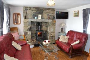a living room with red leather furniture and a stone fireplace at Mc Courts Cottage in Hilltown
