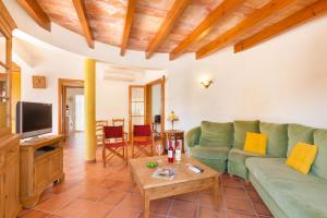 a living room with a green couch and a tv at Villa Blancala 502 in Cala Santandria