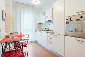 a kitchen with white cabinets and a table with red chairs at S.Antonio Garden Flat with Terrace in Padova