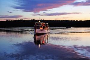 a boat floating on a lake at sunset at Hotel Panorama in Szczecinek