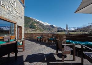 um deque de madeira com cadeiras e mesas num edifício em Apartahotel Tres Quiñones em Sallent de Gállego