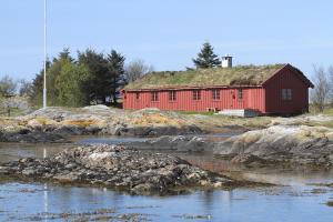un granero rojo con techo de hierba junto a un río en Korsholmen - by Classic Norway Hotels, en Karvåg