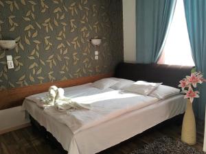 a bed in a bedroom with a white towel on it at Európa Panzió in Mátészalka
