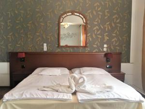 ein Bett mit zwei Handtüchern und einem Spiegel in der Unterkunft Európa Panzió in Mátészalka