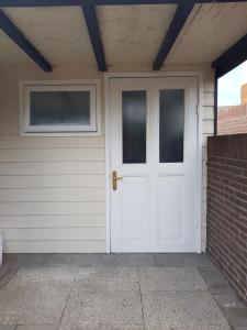 a white door on a house with a brick wall at Mara's Place in Zandvoort