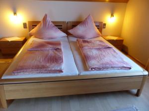 Una cama con sábanas rosas y almohadas. en Ferien Apartment Melcher, en Zeltingen-Rachtig