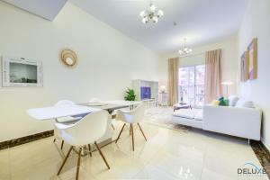 - un salon avec une table, des chaises et un canapé dans l'établissement Vibrant 1BR at Pantheon Boulevard Jumeirah Village Circle by Deluxe Holiday Homes, à Dubaï