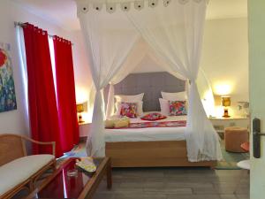 a bedroom with a canopy bed with red curtains at Hotel Djerba Orient in Mezraya