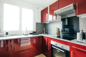 a kitchen with red cabinets and a stove at The Rhuys - Cosy-balcony with superb Loire view - all on foot - Parking in Nantes