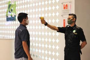 a man taking a picture of another man wearing a mask at Zest Jemursari by Swiss-Belhotel International in Surabaya