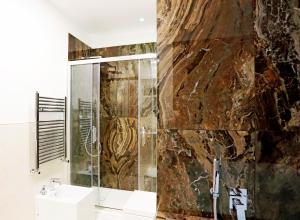 baño con ducha y pared de piedra. en HeMi Suites en Milán