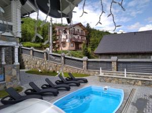 a swimming pool with lounge chairs next to a house at Cottage Diamant Y&M in Palyanytsya