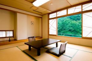 渋川市にあるいかほ秀水園のテーブルと椅子2脚、大きな窓が備わる客室です。