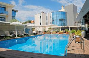 a pool at a hotel with chairs and a building at Best Western Hotel Mediterraneo in Castelldefels