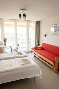 a hotel room with two beds and a red couch at MyRiviéra Apartman in Balatonfüred