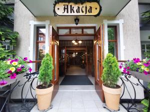 a front door of a restaurant with flowers in pots at Pensjonat Akacja in Kudowa-Zdrój