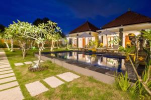 a house with a swimming pool in front of it at Kutuh Manak Guest House in Uluwatu