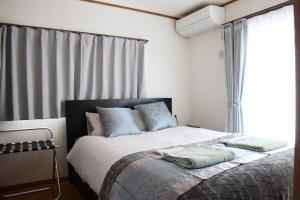 um quarto com uma cama com almofadas azuis e uma janela em HAMA HILLS Shinjuku em Tóquio