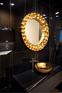 a bathroom with a gold sink and a mirror at Stavros Hotel in Mamaia