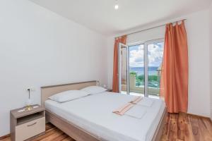 a bedroom with a bed and a large window at Apartments Kate in Duće