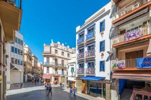 a city street with buildings and people walking on the street at InSitges Center in Sitges