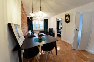 a living room with a table and a couch and a clock at Apartament z Dwoma Sypialniami in Malbork