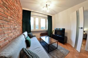 a living room with a couch and a brick wall at Apartament z Dwoma Sypialniami in Malbork
