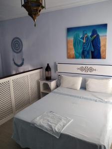 a bedroom with a white bed with a painting on the wall at El apartaito in Sanlúcar de Barrameda
