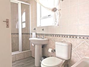 a bathroom with a toilet and a sink and a mirror at Langebaan Beach Towers in Langebaan