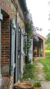 Sainte-Gauburge-Sainte-Colombe的住宿－Au bouton dort，一座带门和鲜花的老砖屋