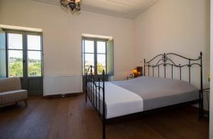 a bedroom with a bed and a chair and windows at Laconian Collection Villa Magoula in Sparti